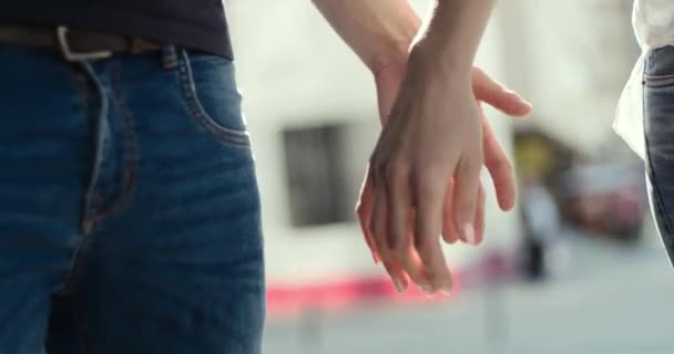 A pair of lovers wearing blue jeans join hands and walk together, close-up. — Stock Video