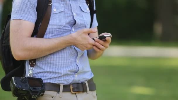 在格仔的恤衫摄影师使用智能手机，在公园里的年轻时髦. — 图库视频影像