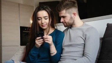 Genç çift evde, telefon onun elinde tutan kız rahatlatıcı.