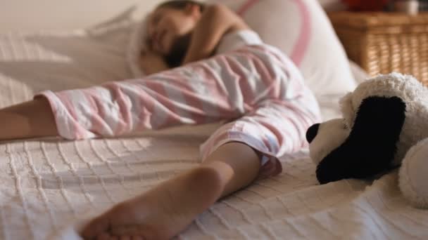 Портрет маленькой девочки, отдыхающей на кровати в своей спальне — стоковое видео