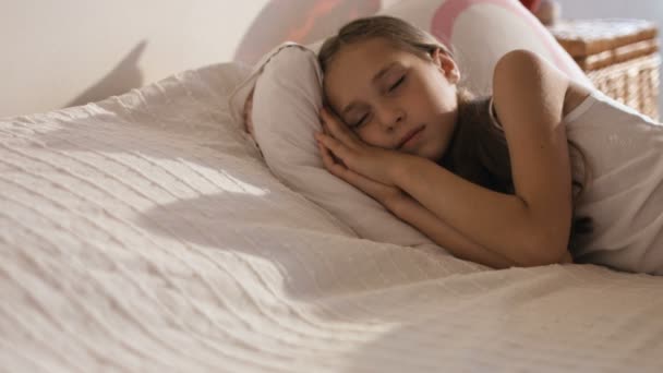 Niña divertida acostada en la cama sonriendo después de dormir, primer plano — Vídeo de stock