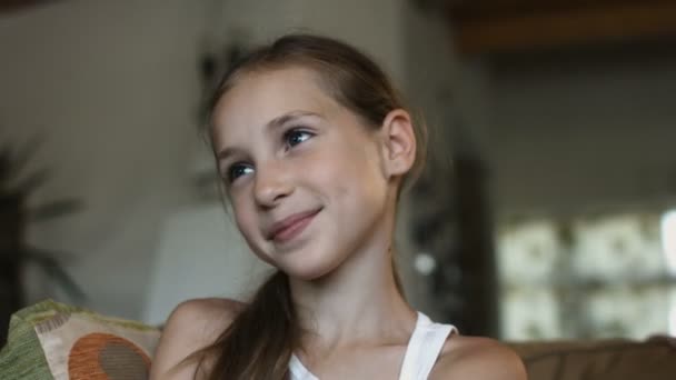 Close up face Littlecaucasian sorrindo menina assistindo TV no sofá sozinho . — Vídeo de Stock