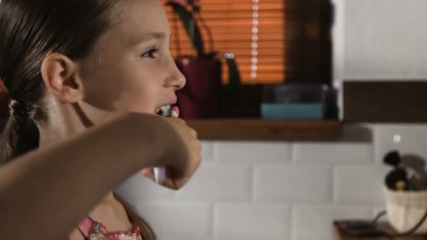 Menina em pijama rosa no banheiro escovando os dentes, close-up — Vídeo de Stock