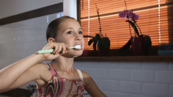 Menina em pijama rosa no banheiro escovando os dentes, close-up — Vídeo de Stock