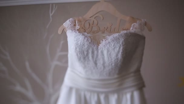 Beautiful white luxury wedding dress on hanger on the background of light interior — Stock Video