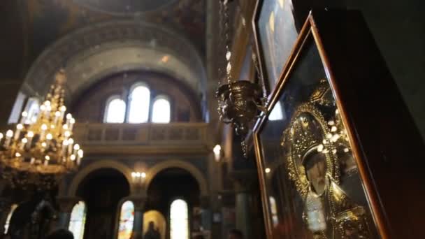 Interior of church. Candles chandelier near the ancient icon framed with the gold — Stock Video