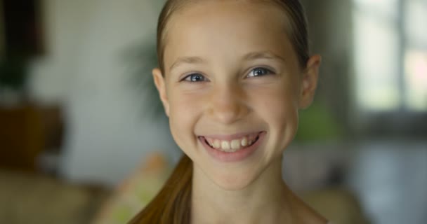 Закрытая девочка часто улыбается и смотрит в камеру — стоковое видео