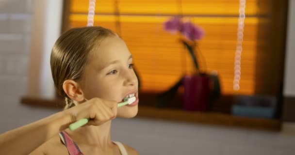 Niña linda usando pijama rosa cepillándose los dientes — Vídeos de Stock