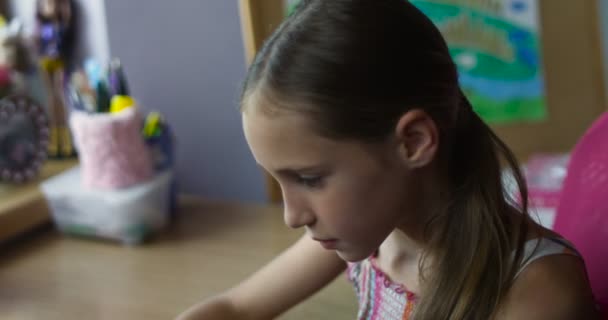 Kleine lächelnde Schülerin sitzt mit Smartphone am Schreibtisch im Kinderzimmer und spielt Spiele — Stockvideo