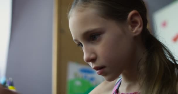 Smartphone-játék óvoda pultnál ülő kis mosolygó iskoláslány — Stock videók