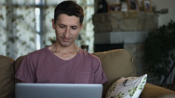 Az ember egy videó chat üdvözlés, amelyek a beszélgetőpartner ül a kanapén — Stock videók