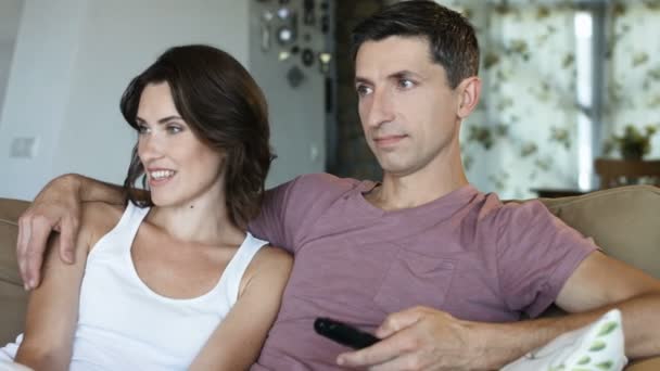 Gros plan de beau couple relaxant regardant la télévision à la maison sur le canapé avec étreinte — Video