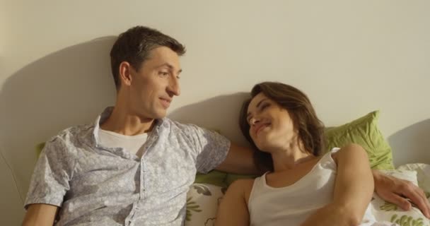 Счастливая семья, мать, отец и дочь отдыхают на белой кровати — стоковое видео
