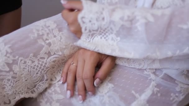 Handen van de mooie bruid in witte badjas. Schoonheid model meisje in bruiloft kleed. Vrouwelijke portret met manicure. Close-up dames armen. Schattige dame binnenshuis — Stockvideo