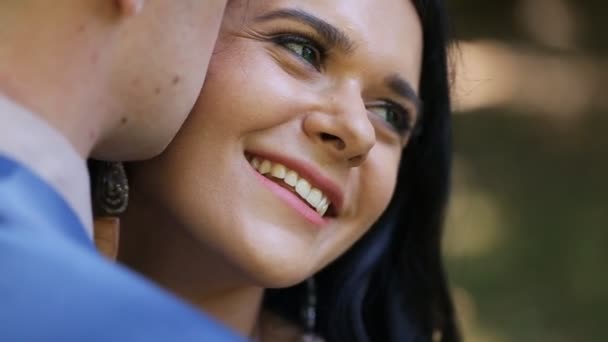 Close-up hermosa novia morena sonriendo mientras el novio susurra cumplidos a ella — Vídeo de stock
