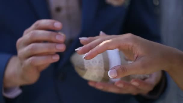 Anéis de casamento de ouro e mãos de casal recém-casado Close up on hand of a man put on a engagement ring on the finger of the bride — Vídeo de Stock