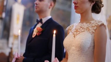 Beyaz duvak ve taç ve yakışıklı damat, mum portre tutan güzel şehvetli sarışın gelin. Kilisede düğün töreni