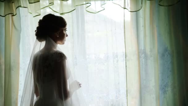 Silhouette di una bella sposa in abito bianco contro la finestra in hotel — Video Stock