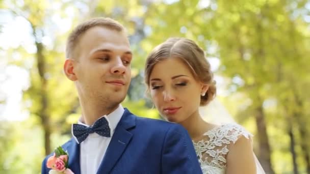 Emocional hermosa novia abrazando a su novio recién casado por detrás, puesta de sol en el parque de otoño primer plano — Vídeos de Stock