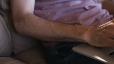 Teknoloji, ev ve yaşam tarzı kavramı - dizüstü bilgisayarla çalışan ve evdeki koltukta oturan adama yakın çekim