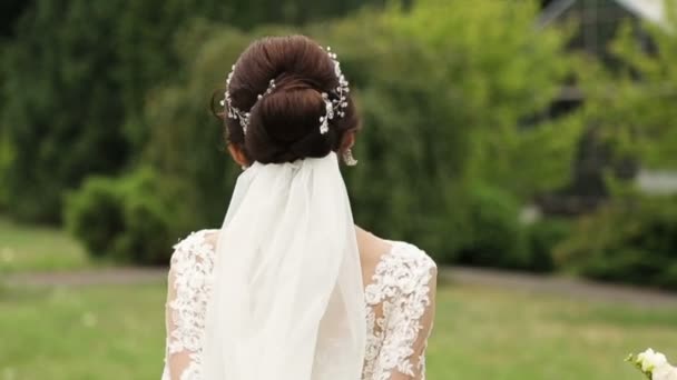 Portrait of a bride in wedding dress with flowers in a sunny park. — Stock Video