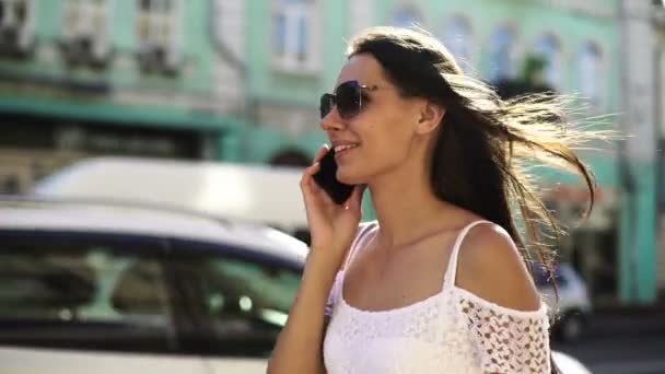 Charming woman smiling and talking on the phone on the background of busy street — Stock Video