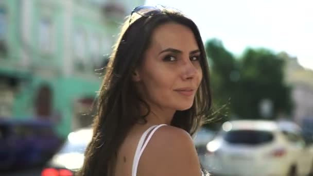 Όμορφη μελαχρινή κοπέλα περπατάει στον δρόμο της Ευρωπαϊκής πόλης, κοιτάζοντας πίσω. — Αρχείο Βίντεο
