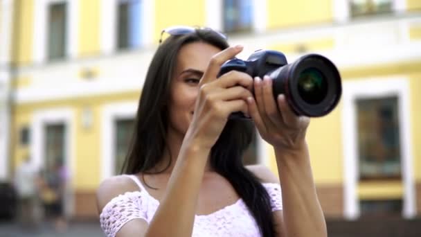 Przyjemna kobieta uśmiechający się trzymając aparat, biorąc zdjęcie na zewnątrz hotelu city street — Wideo stockowe
