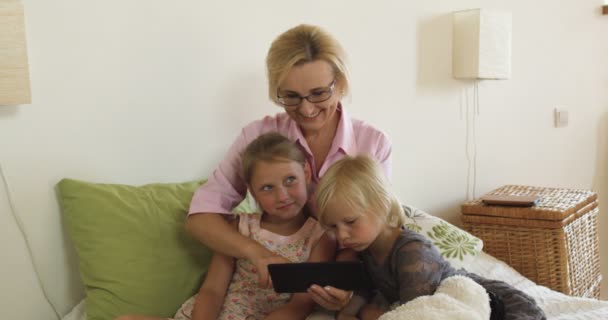 Feliz abuela con los niños jugando juegos en la tableta en casa — Vídeos de Stock