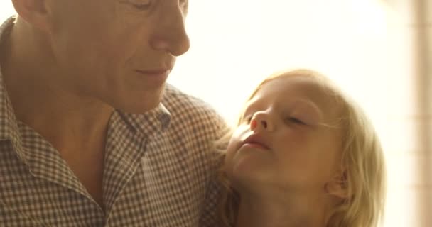 Il nonno tiene in braccio e gioca con il nipotino. Vecchio con bambino carino seduto in camera luminosa — Video Stock