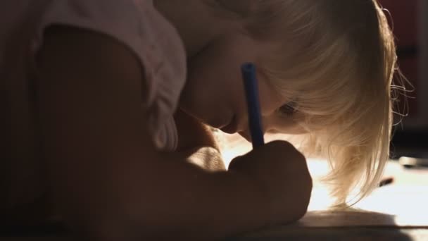 Lugn liten flicka ritning liggande på golvet i soliga vardagsrummet, närbild — Stockvideo