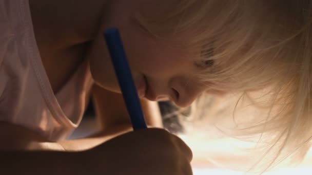 Calm little girl drawing lying on the floor in the sunny living-room, close-up — Stock Video