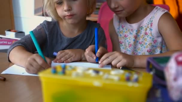 Сибірки малюють кольоровими олівцями, сидячи за столом вдома в дитячій — стокове відео