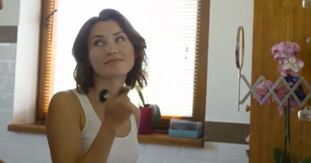 Jolie femme appliquant le maquillage sur la joue 