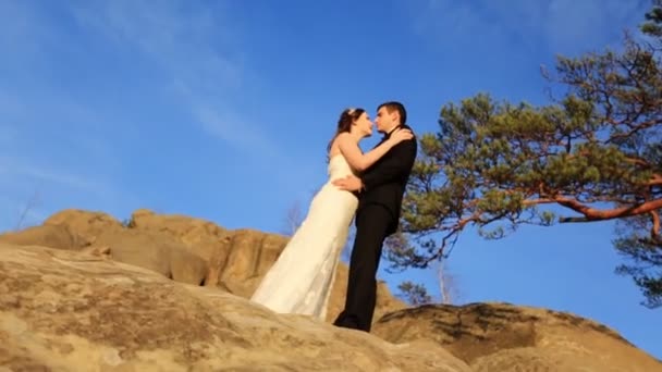 Ρομαντικό παραμύθι ζευγάρι νεόνυμφων ποζάρουν στο ηλιοβασίλεμα με φόντο βουνά — Αρχείο Βίντεο