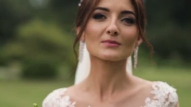 Gelinlik gelin bir güneşli parkta çiçekli portresi.