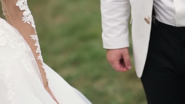 緑の背景に手を繋いでいる結婚式のカップルがスローモーションで撮影 — ストック動画