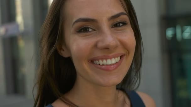 Maravillosa mujer sonriente con un aspecto encantador y maquillaje natural mirando a la cámara y el viento moviendo su cabello — Vídeo de stock