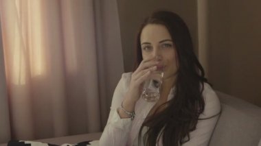 Gülümseyen kız evde bir kanepede oturan ve kameraya bakarak İçmesuyu