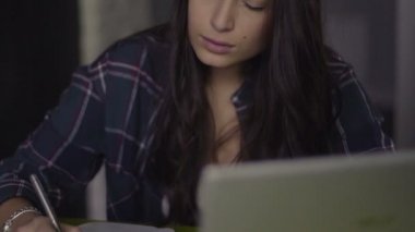 Bir öğrencinin öğrenmesini hatta evde masasında oturan bir defter notlar alarak dizüstü bilgisayar ile portresi