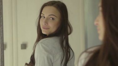 Genç, güzel esmer kadın aynanın karşısında kendini kontrol ediyor.