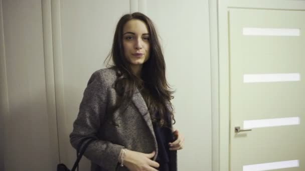 Donna sorridente in cappotto guardarsi allo specchio e uscire di casa — Video Stock