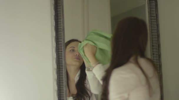 Mujer morena sonriente limpiando espejo en casa, vista desde atrás — Vídeo de stock