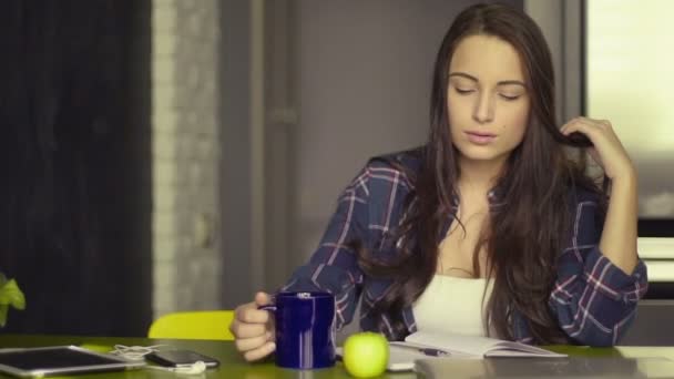 Ev konseptinde çalışmak. Girişimci iş kadını. Yazıyor, not alıyor, masada kahve içiyor. — Stok video