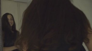 Bir ayna, yavaş hareket yanında dönen uzun koyu saçlı güzel mutlu kız