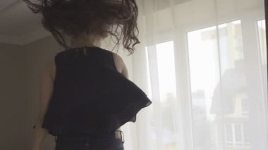 Uzun saç atlama ile Komik mutlu esmer kız, iplik ve yatakta eğlenmek