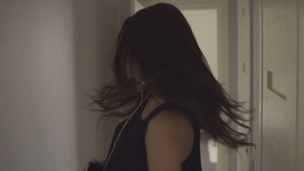 Charmante Frau oder Teenager-Mädchen mit Kopfhörern, die Musik vom Smartphone hören und zu Hause im Bett tanzen — Stockvideo