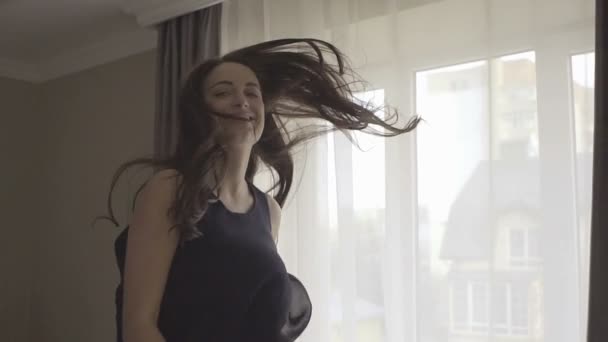 Grappig gelukkig brunette meisje met lang haar springen, spinnen en plezier hebben in bed — Stockvideo