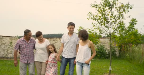 Una familia, con padres, hijos y abuelos, divirtiéndose caminando en el jardín — Vídeo de stock