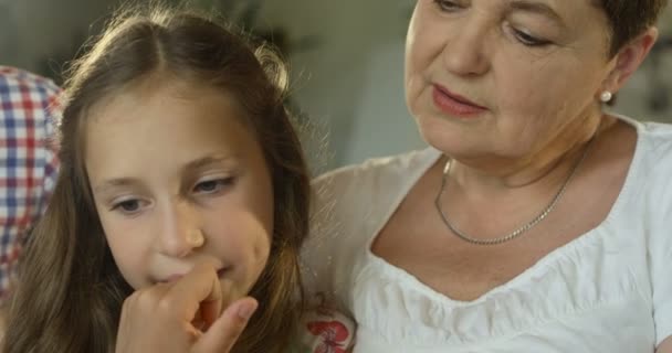 Širší rodiny dědeček, vnučka a babička při pohledu na jejich fotografie album v obývacím pokoji — Stock video